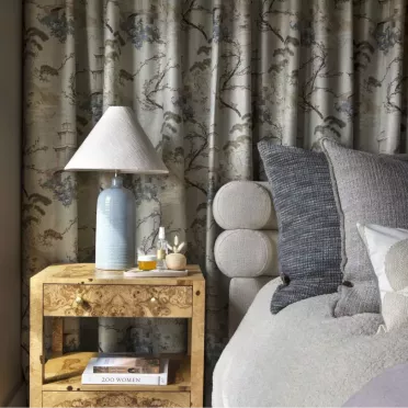 Bed with gray pillows in front of floral curtains
