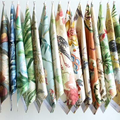 Colorful floral fabric samples hanging vertically from a clothesline.