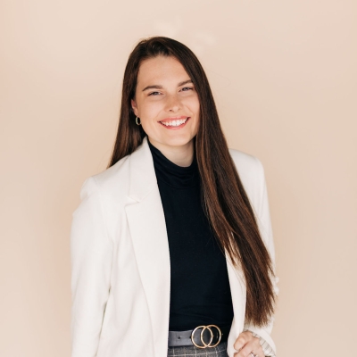 Girl with long brown hair smiling wearing a white blazer.