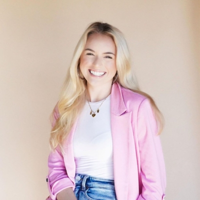 Blonde girl smiling with pink blazer.